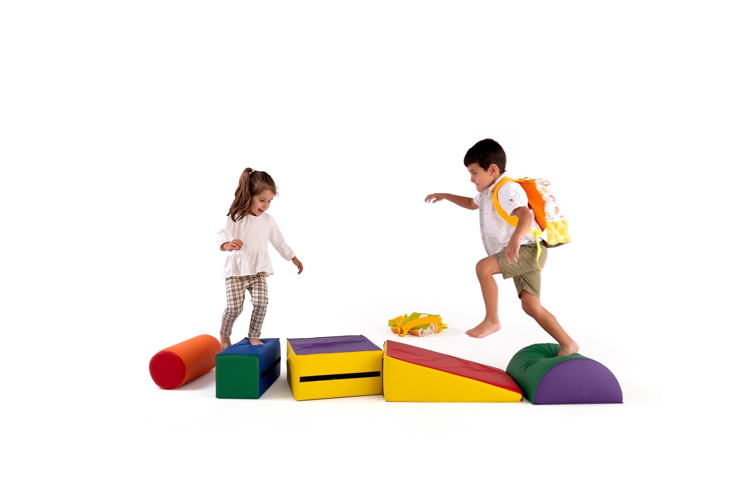 Two young children playing on colourful foam blocks, with one wearing a Twisty Kids backpack. A fun, screen-free activity promoting creativity and active play.