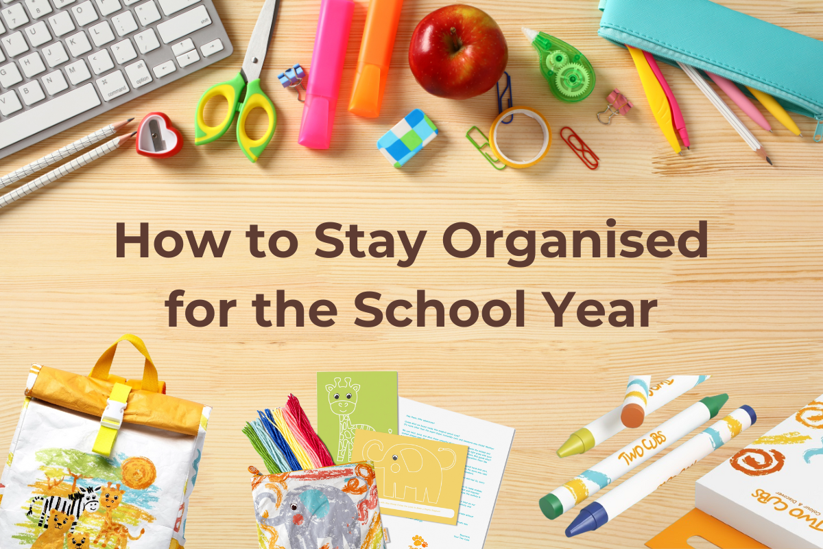 Flat lay of back-to-school essentials, including a Twisty Kids safari backpack, wet bag, crayons, stationery, and activity cards, arranged on a wooden desk.