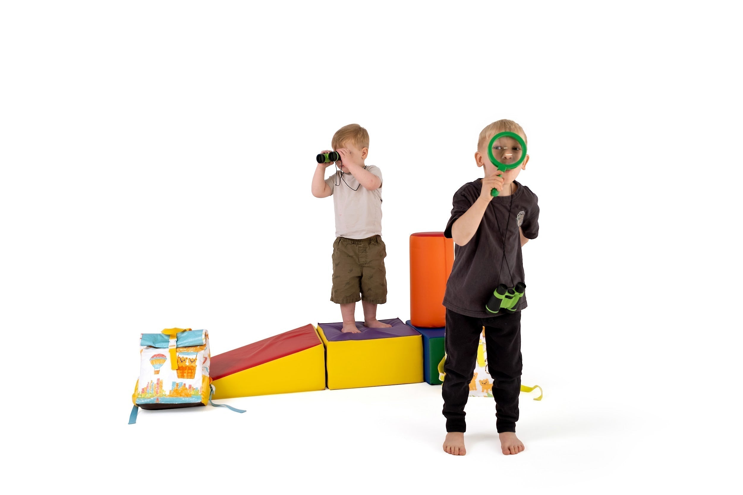 Two kids exploring, alongside a colourful TWO CUBS kids backpack