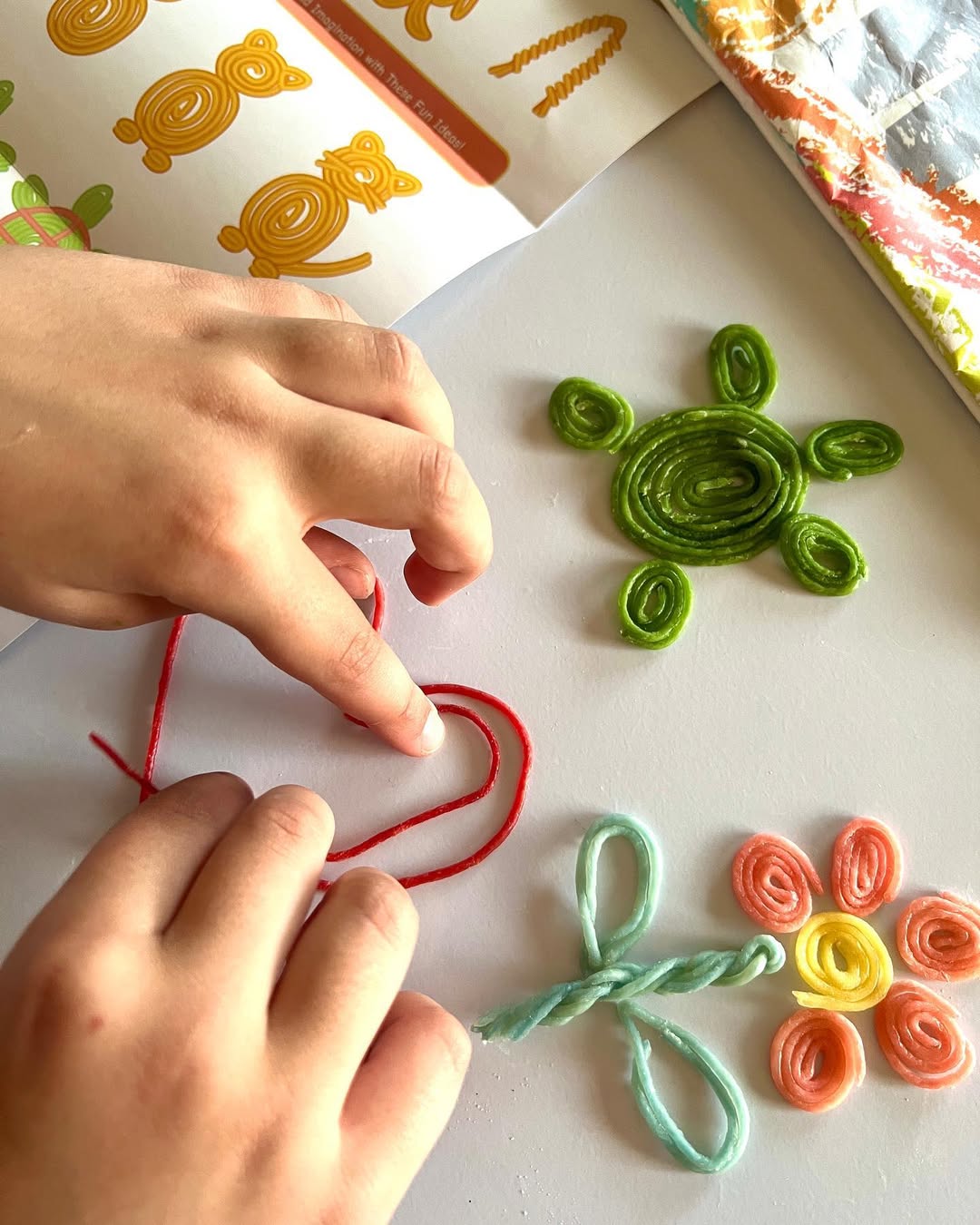 Child playing with Twisty Kids reusable wax sticks creating shapes for hands-on learning activity 1