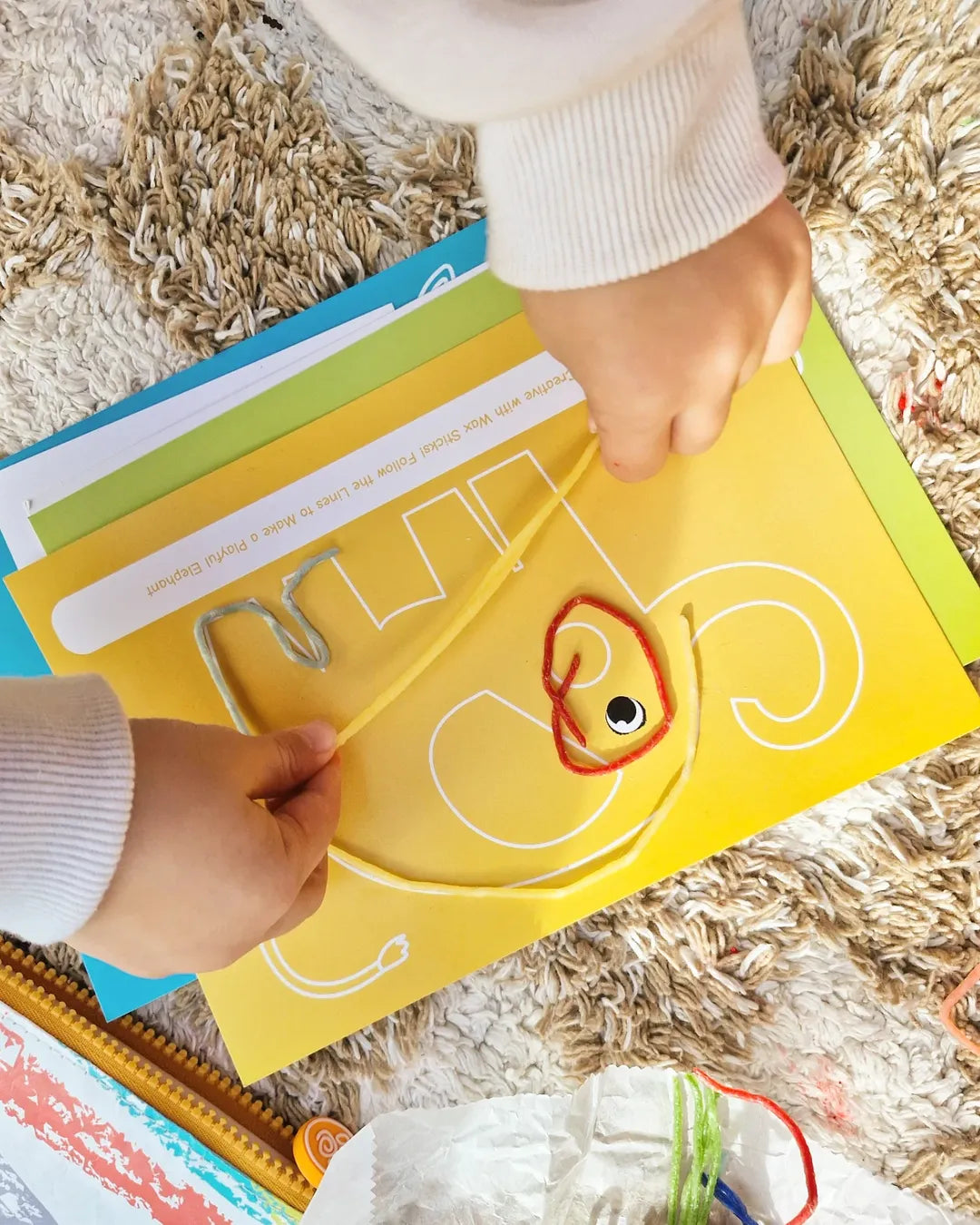 Child's hands creating shapes with Twisty Kids reusable wax sticks, a screen-free toy that supports fine motor skill development
