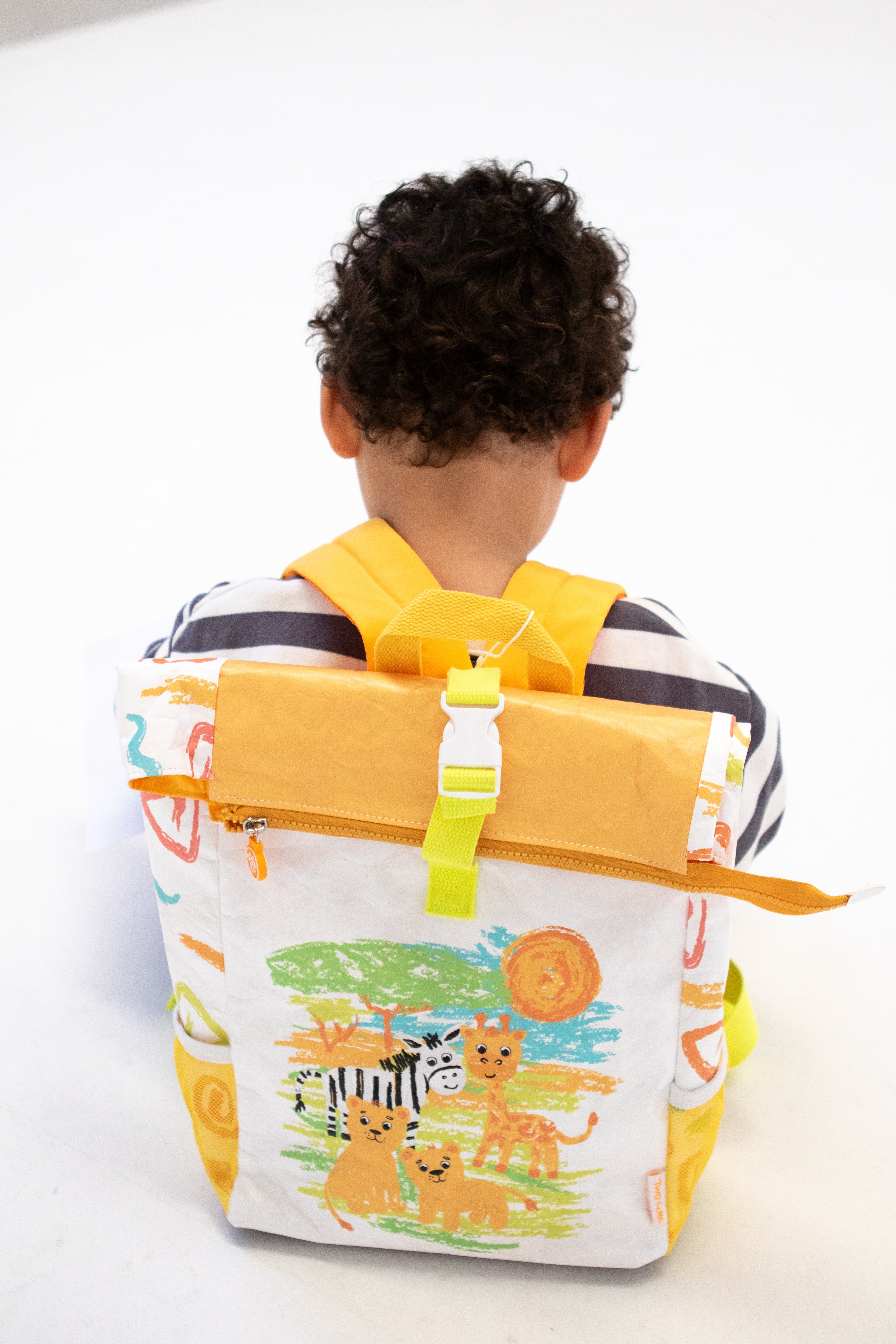 Child wearing Twisty Kids backpack with a colorful design of animals and nature on a white background