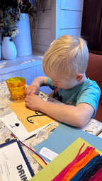 Child playing with wax sticks at restaurant table for hands-on learning activity 1