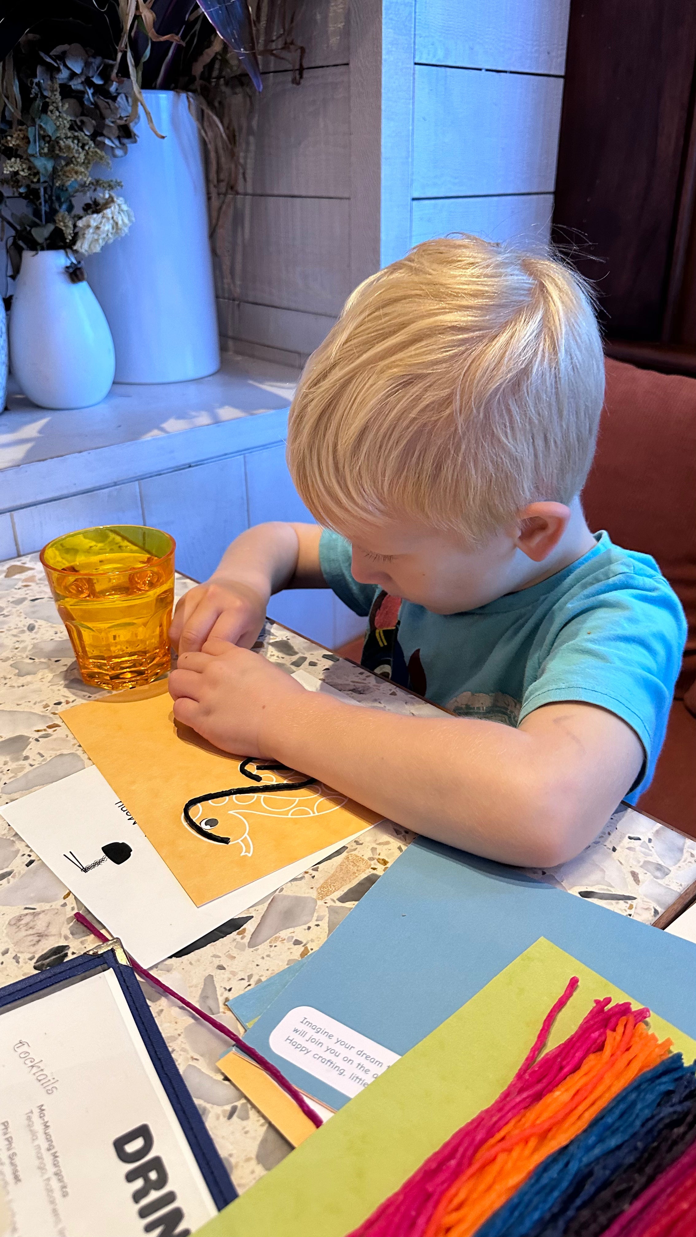 Child playing with wax sticks at restaurant table for hands-on learning activity 1